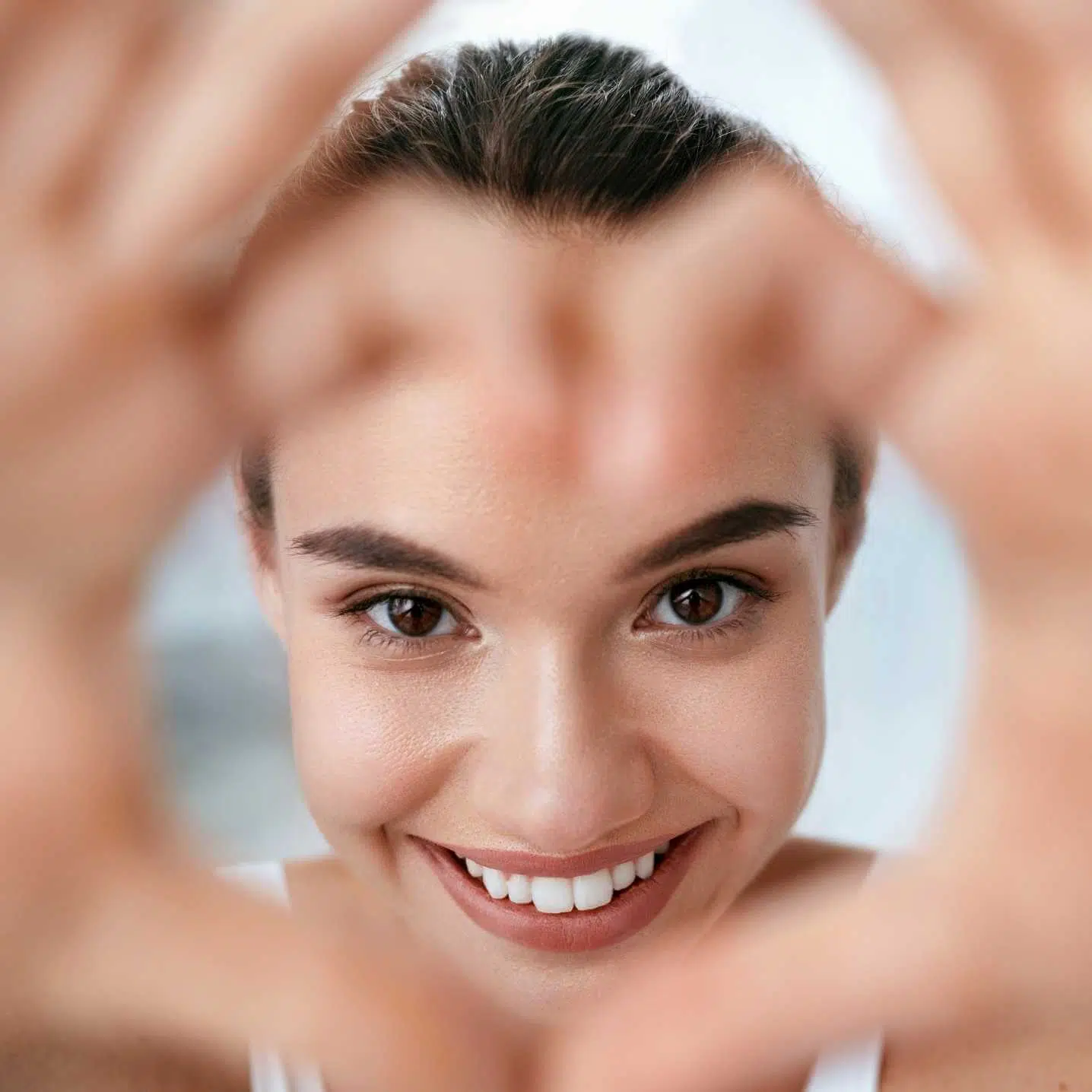 Happy patient making a heart shape with hands representing love for natural bio-regenerative care results and healthy skin