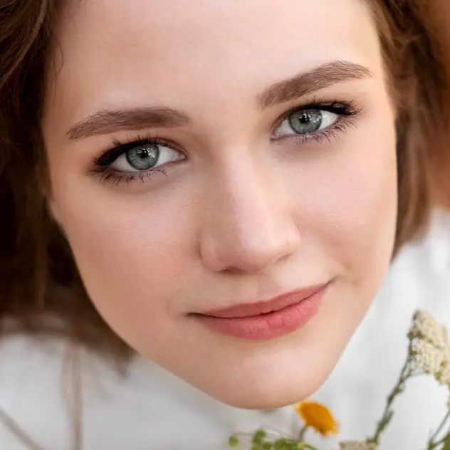 Close-up of a woman holding a flower representing the natural ingredients in Čuvget skin care products for daily self-care